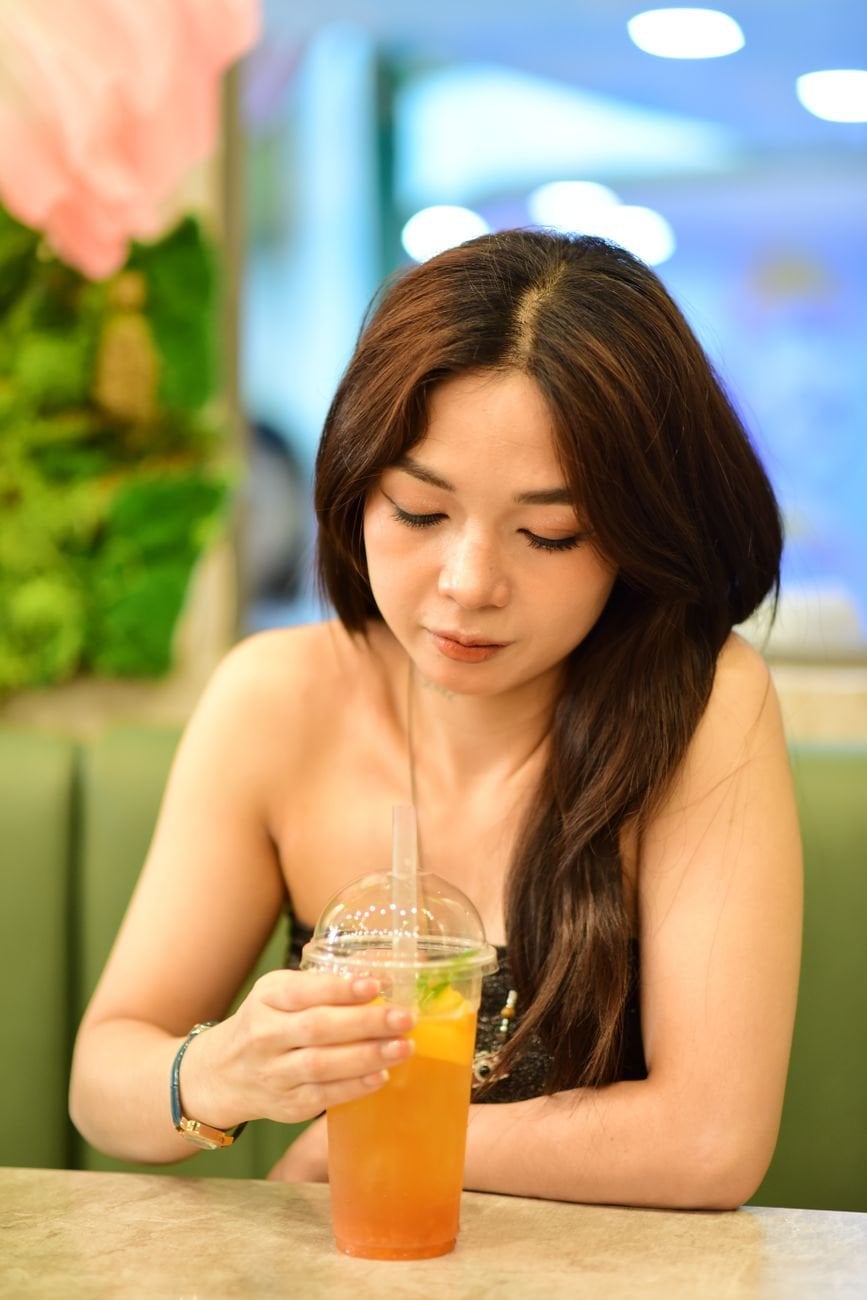 A young woman in a cafe enjoying a refreshing iced tea drink in a relaxed setting.